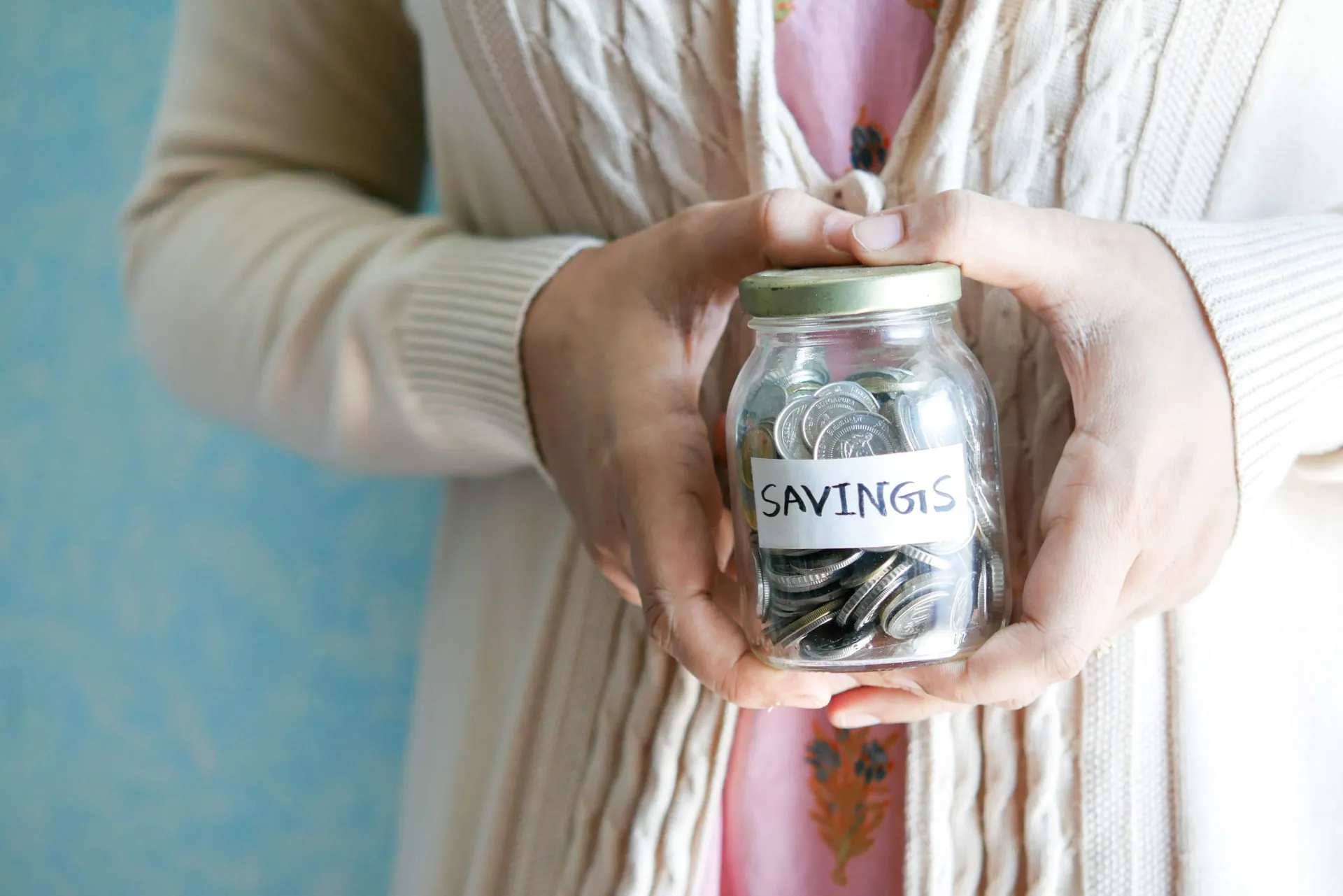Saving For Retirement.
Woman holding a jar full of coins with a tag reading savings. Photo by Towfiqu barbhuiya on Unsplash