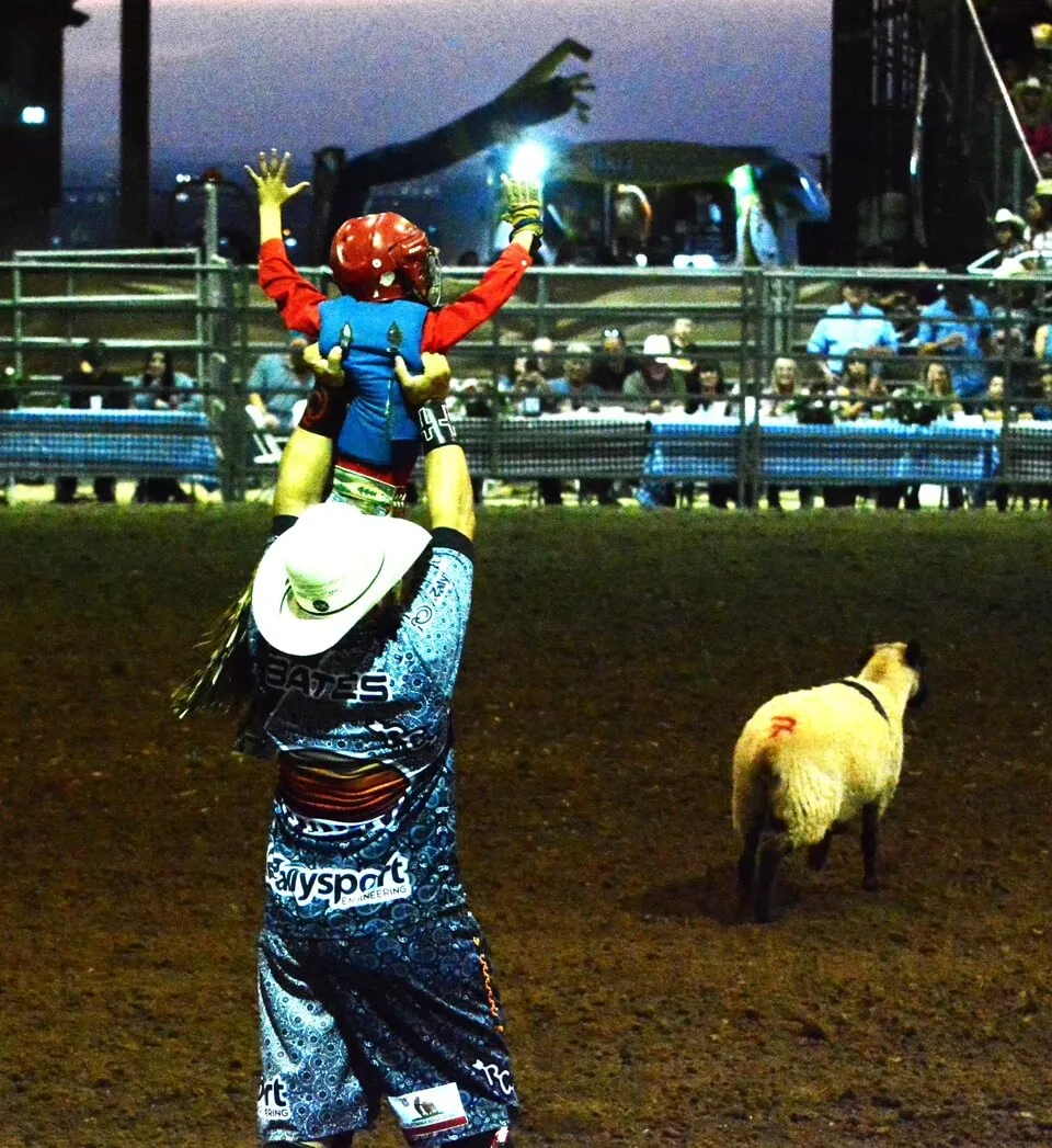 A rodeo clown holds Ryder Hallam aloft after Hallam’s successful ride in mutton busting Sunday night at the Norco Fair.
Credit: Photo by Gary Evans
