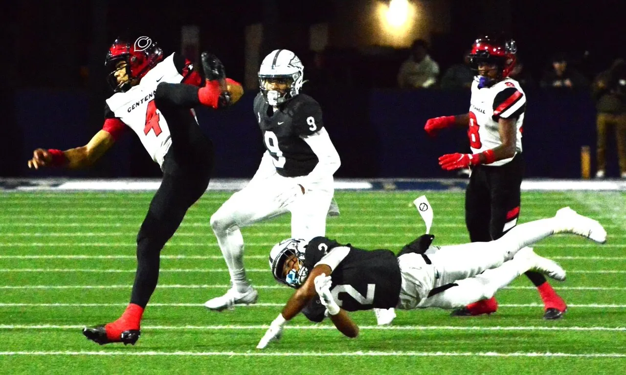 Corona Centennial vs St. John Bosco. Centennial QB Husan Longstreet (4) is sent flying after a low hit by St. John Bosco’s Tamal Johnson (2) during the fourth quarter of the Braves 43 – 42 CIF Division 1 semi-final victory over the Huskies. Bosco’s Dillon Rickenbacker (9) and Centennial’s Cory Butler Jr. (8) watch the play. Photo by Gary Evans