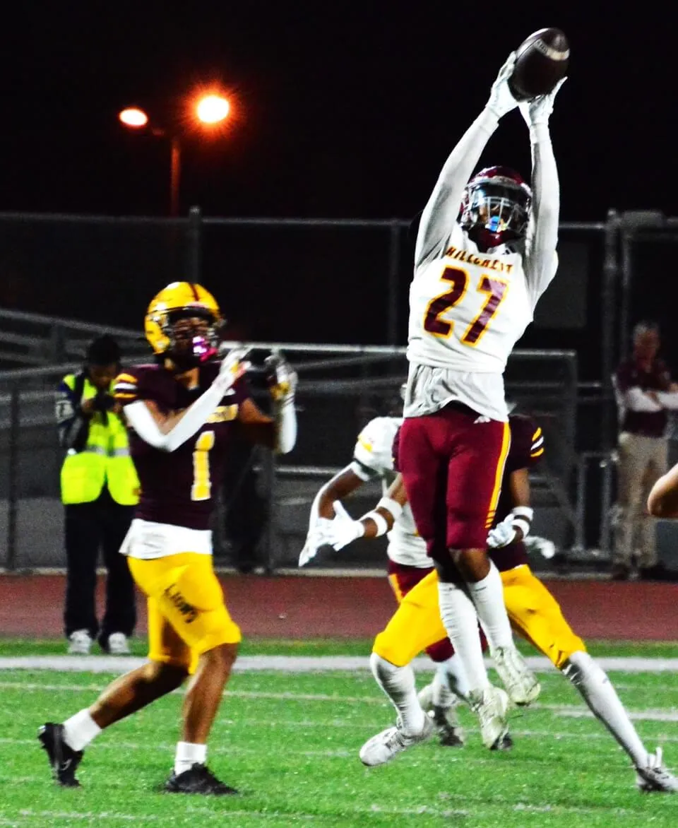 Hillcrest defender James Maldonado (27) makes a leaping interception in front of Arlington’s Eric Barajas (1) during the Trojans 31 – 21 victory over the Lions. Photo by Gary Evans