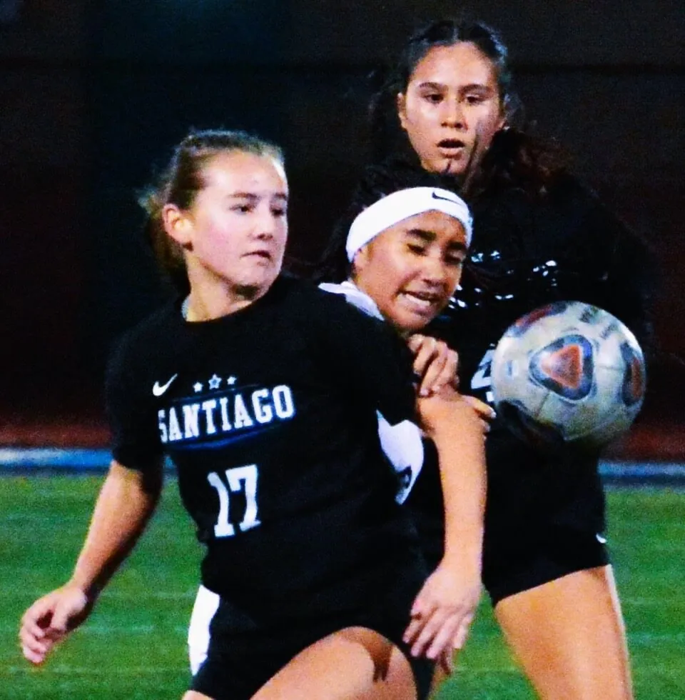 Corona Santiago’s Maddy Saruwatari (17) and Brianna Garcia (4) sandwich a Downey player during the Sharks victory.