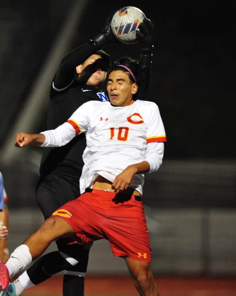 Norco soccer goalie Diego Salgado grabs the ball over the head of Corona's Kyros Vazirian in front of the Norco goal in a Big VIII League game won by the Panthers, 2-1, Friday. Credit: Photo by Jerry Soifer