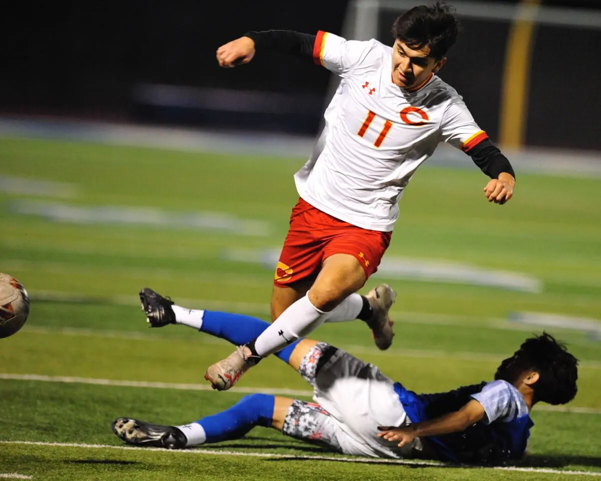 Corona's Miguel Rocha leaps over a Norco player in a Big VIII league game won by Corona, 2-1, Friday. Credit: Photo by Jerry Soifer