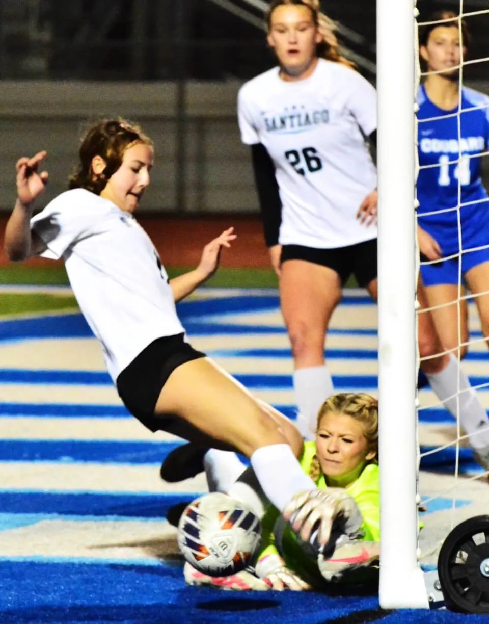 Corona Santiago’s Maddy Saruwatari (left) misses on a score as Norco goalie Eliana Rodriguez (middle) swats the ball away after it bounced off Rodriguez and both went for the bouncing ball. The Sharks defeated the Cougars 3 – 0. Santiago’s Jordan Goldstein (26) and Norco’s Alexa Lopez (14) watch. Credit: Photo by Gary Evans