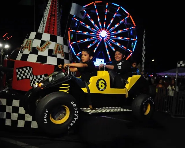 Young boys enjoy a dune buggy-themed spinning ride at Corona’s St. Edward Catholic Church Carnival last Saturday. Credit: Photo by Jerry Soifer