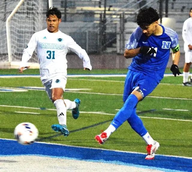 Caption: Norco’s Abraham Garcia (11) punches in his rebound for a goal off a penalty kick after Santiago goalie Gabriel Mateos blocked it. Isaiah Guieb (31) watches the score. Playing in a driving rain all game, the Cougars defeated the Sharks 2 – 0 in the first round of the CIF playoffs.
Credit: Photo by Gary Evans