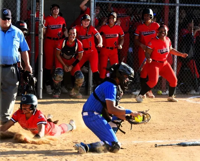 Centennial’s  Nele Sanchez (left) slides in safe at home while Norco catcher Ashley Duran handles the throw.  The Centennial bench celebrates including Risa Hernandez (48), Aislynn Guzman (8), and Jasmine Estrada (4).  The Cougars defeated the Huskies 4 – 2.  
Credit: Photo by Gary Evans
