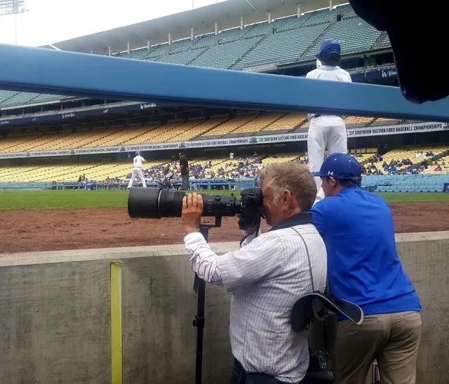 Jerry Soifer shoots the 2019 CIF baseball championship game from the photographer’s well at Dodger Stadium. In the classic title tilt, Norco fell to Rancho Santa Margarita in 12 innings. Credit: Photo by Gary Evans