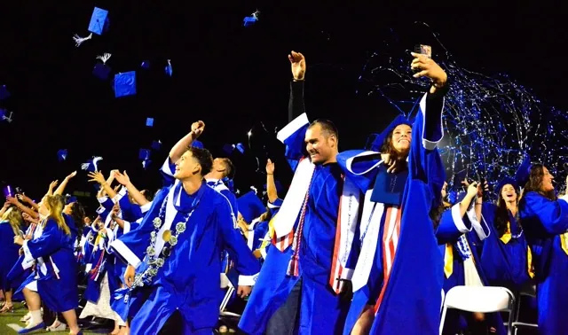 Norco High Class of 2025 Graduates Conner Hernandez (center) and Riley Hernandez (taking selfie) celebrate as caps and confetti streamers fly as the Cougars’ commencement ceremony concludes. Credit: Photo by Gary Evans