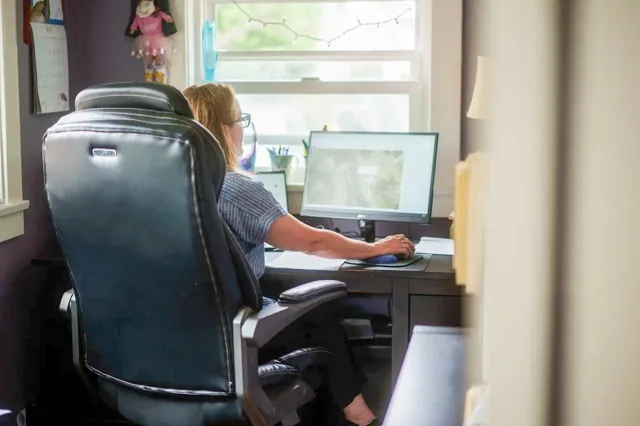 California Health Insurance. Heather Altman works at her desk, inside her home office in Long Beach on July 11, 2025. Credit: Photo by Jules Hotz for CalMatters