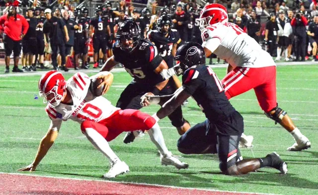Mater Dei QB Ryan Hopkins (10) keeps from falling into the end zone for a safety after being hit by Centennial’s Jonathan McKinley II (right). Linebacker Lucky Schirmer (55) is about to keep Hopkins at the one-yard line. Two plays later, Hopkins fumbled the ball in the end zone, McKinley and Hopkins’ feet squibbed the ball out of the back of the end zone which gave the Huskies a 33 – 7 lead.