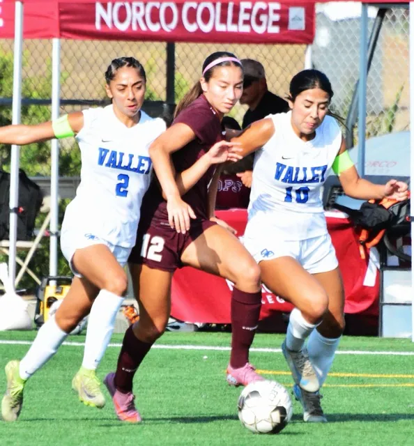 Featured Photos 10-03-2025. San Bernardino Valley College players Sienna Villalobos (2, left) and Faith Facio (10, right) scrunch Norco’s Leila Martinez (12) during the visiting Wolverines’ 2 – 0 victory over the Mustangs in Norco.
