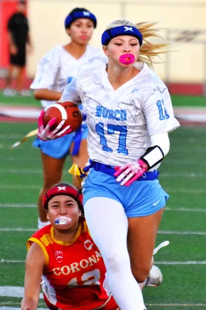 Corona’s Olivia Arroyo (lower left) dives and misses the flag of Norco’s Ryley Rocheleau during a punt return. The Cougars extended their winning streak to 12, defeating the Panthers 30 – 6.