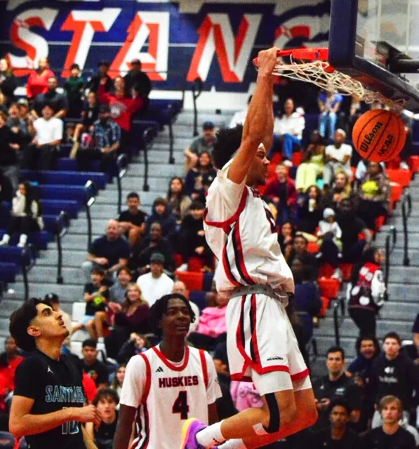 Santiago’s Dorian Nawabi (10) and Corona Centennial’s Carter Brown (4) watch Kai Patton (0) make an emphatic slam dunk. Tied at halftime at 28, the Huskies dominated the 2nd half, winning 59 to 38. Credit: Photo by Gary Evans