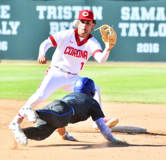 Corona shortstop Trey Ebel (top) eyes the ball before making the catch and tag of Norco’s Dylan Seward (2) as he tries to steal second base.