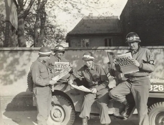 May 8. Four MPs take a break along a German road to read in the "Stars and Stripes" newspaper about the Nazi surrender. Credit: U.S.Army