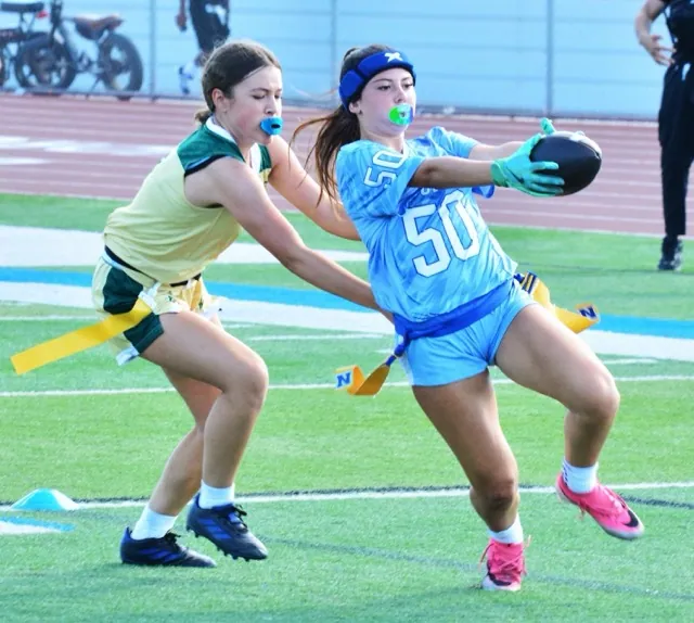 Norco’s Brooklyn Rivera (50) stretches the ball toward the goal line for a touchdown while a Lake Elsinore Lakeside defender reaches futilely for her flag. The Cougars blanked the Lancers 41 – 0.