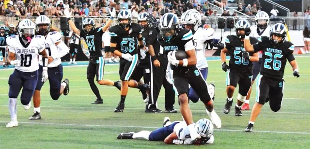 With Silverado’s Andrew Scott (10), Isaac Muasau (90) and Zion Millican (5) giving chase, Santiago’s Isaiah Hughes leaves the Hawks Jose Escobar (0) grounded as he heads for a touchdown. Sharks teammates Tyler Jiricek (41), Ricky Rivera (68), Emiliano Angeles (50) and Ivan Rosado (26) have already begun to celebrate.